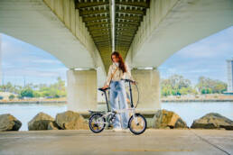 advertising photography of woman standing next to a collapsible dahon bike