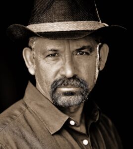 portrait photographer's shot of latino man with hat is sepia