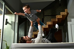 lifestyle photography of a boy pretending to fly while father is holding him