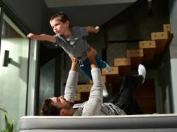 lifestyle photography of a boy pretending to fly while father is holding him