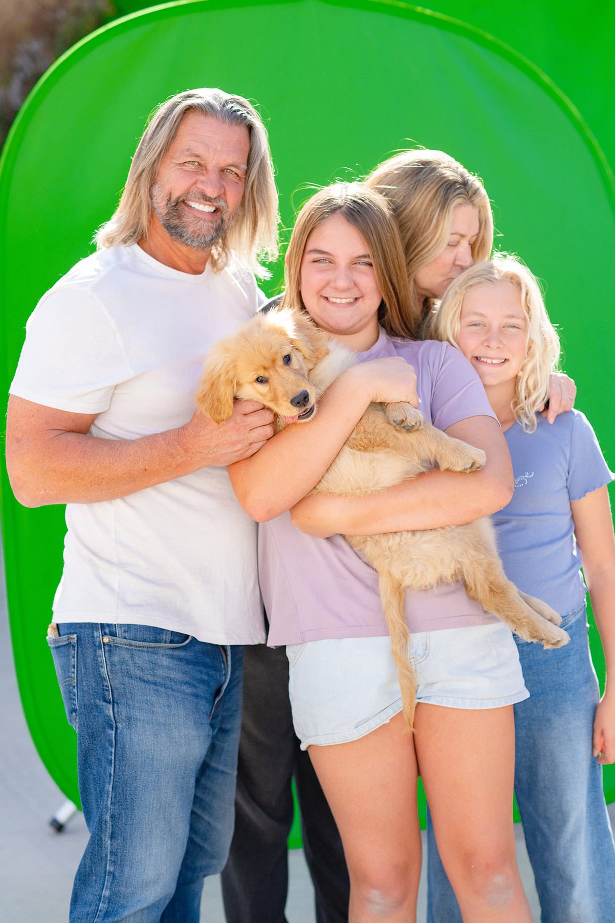 Young caucasian family with Golden Retriever photographed against a greenscreen.